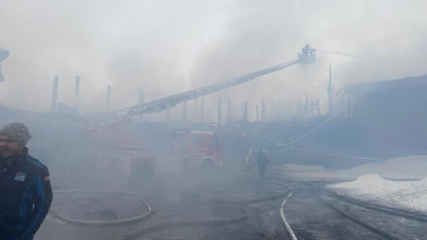 Die Feuerwehr agiert mit der Drehleiter im dichten Qualm