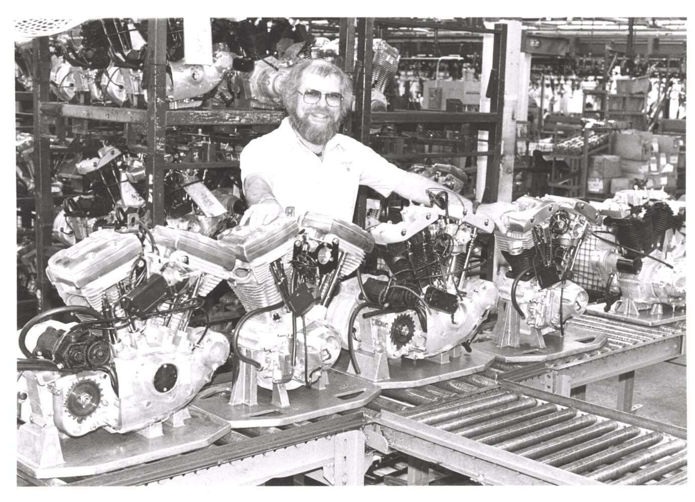 a man standing in front of several machines - Willie G. Davidson 1984 mit Shovelhead und Evolution Motoren