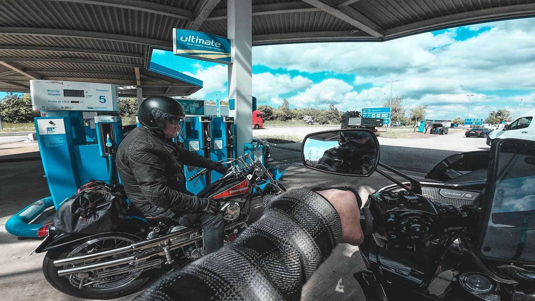 a man sitting on a motorcycle at a gas station