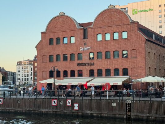 Mit der CVO Street Glide 2025 quer durch Polen Rotes Backsteingebäude am Wasser