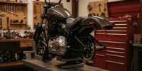 KessTech unter neuem Holding-Dach organisiert Harley-Davidson Softail auf der Werkstattbühne mit sichtbarem Antrieb und Werkzeugwand im Hintergrund.